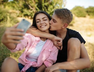 Male teen kissing a female teen in a park