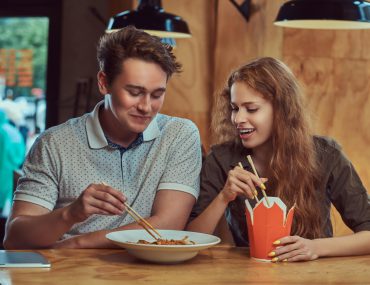 Young man and woman on a date and eating spicy noodles in a Dallas restaurant