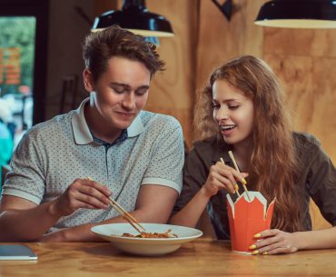 Dallas Hookup | Where to Pick Up and Date Girls in Dallas Young man and woman on a date and eating spicy noodles in a Dallas restaurant