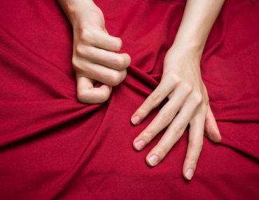 Hand grabbing bedsheet during sex