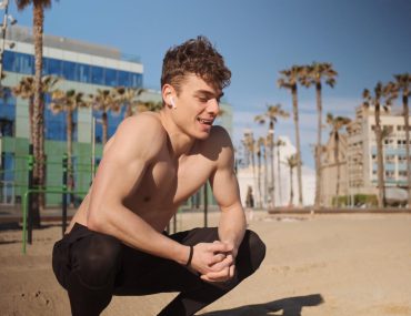 Sporty man with wireless earphones resting during outdoor workout