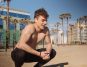 Sporty man with wireless earphones resting during outdoor workout