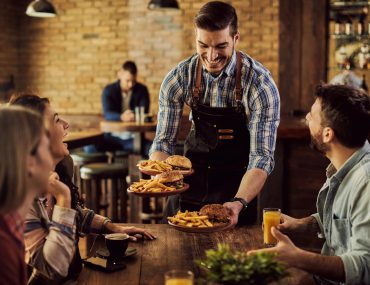 A waiter serving food to a couple on a date