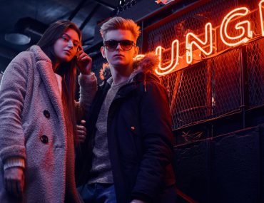 Young man and woman dressed casually standing in front of a lounge at night