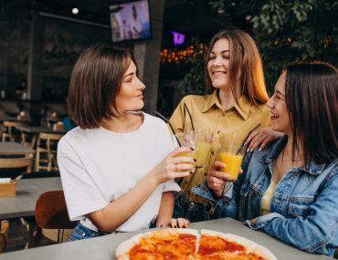 girl friends having pizza at a bar at a lunch time