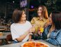 girl friends having pizza at a bar at a lunch time