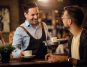 A waiter offering a customer a cup of coffee in a cafe