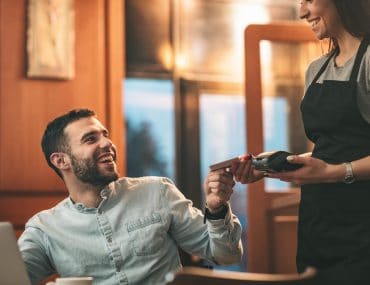 Waitress serving coffee to a man waiting for his date in a cafe
