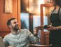 Waitress serving coffee to a man waiting for his date in a cafe
