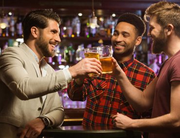 Male friends clinking beer mugs together