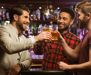Male friends clinking beer mugs together