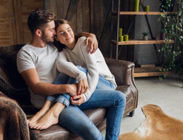 Couple wearing casual outfit sitting on a couch