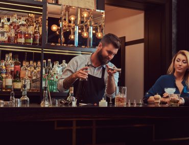 A bartender serving a young woman at the bar counter