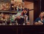 A bartender serving a young woman at the bar counter