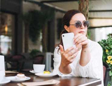 A young woman in a bar taking a picture with her phone