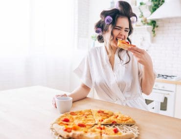 A sugar baby eating pizza in her kitchen