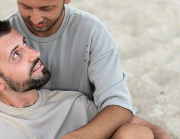 Gay couple holding each other at the beach