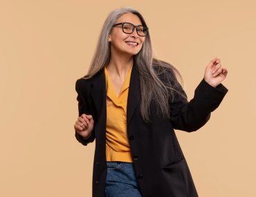 A fashionable senior woman dancing against a