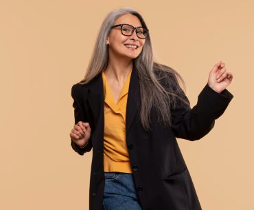 A fashionable senior woman dancing against a