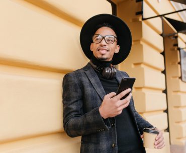 Young man wearing stylish black suit using his android phone