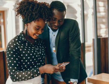 Two black couples using at their phone