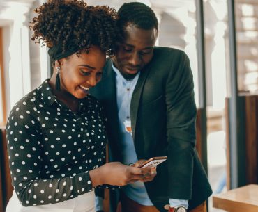 Two black couples using at their phone