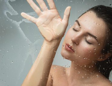 Sensual young woman captured through wet glass