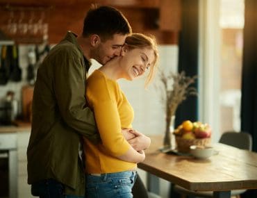 A man embracing his partner in their home