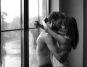 Side view of a kissing couple by the window