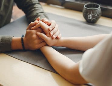 A couple holding hands on a table in a cafe