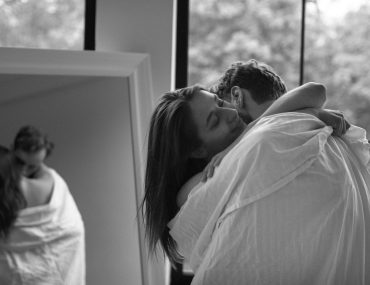 Side view of a couple hugging with a bedsheet over them