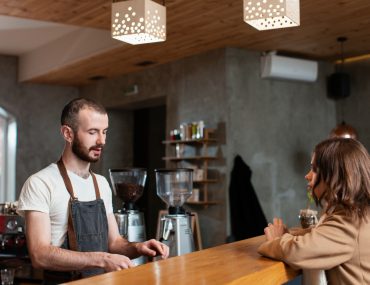 bartender in apron serving coffee to a young woman