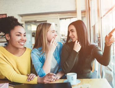 Three girls sitting and talking in a café