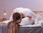 Man kissing a woman on her neck, while on a bed